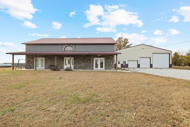 view of front facade with a front lawn, a garage, an outbuilding, and french doors