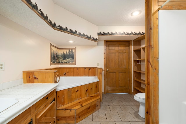 bathroom with vanity, tile patterned flooring, a washtub, toilet, and a textured ceiling