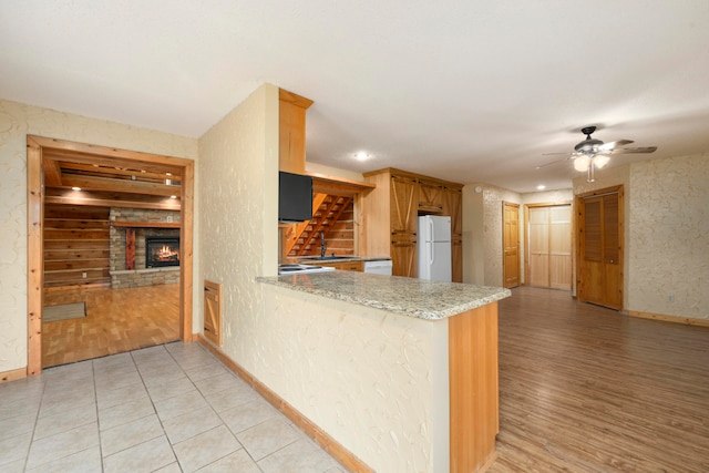 kitchen featuring ceiling fan, white refrigerator, light hardwood / wood-style floors, and kitchen peninsula