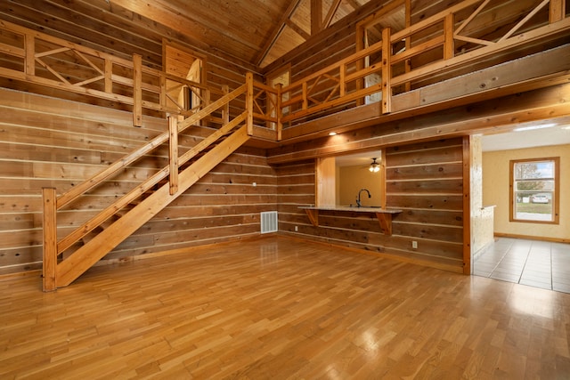 unfurnished living room featuring hardwood / wood-style flooring, wood walls, lofted ceiling, and wood ceiling