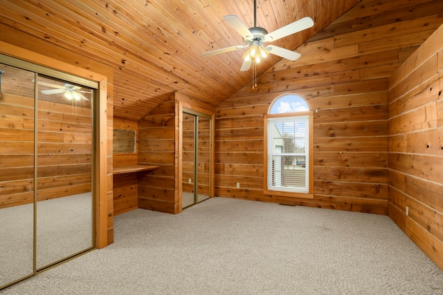 unfurnished bedroom with ceiling fan, wooden ceiling, wood walls, vaulted ceiling, and carpet