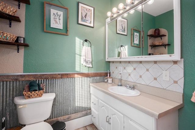 bathroom featuring vanity, toilet, and tasteful backsplash