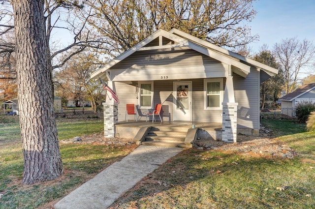 bungalow-style home featuring covered porch and a front yard