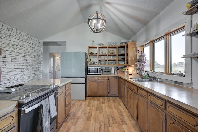 kitchen with appliances with stainless steel finishes, light wood-type flooring, sink, pendant lighting, and lofted ceiling