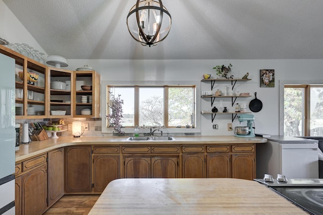 kitchen featuring vaulted ceiling, sink, a healthy amount of sunlight, and decorative light fixtures