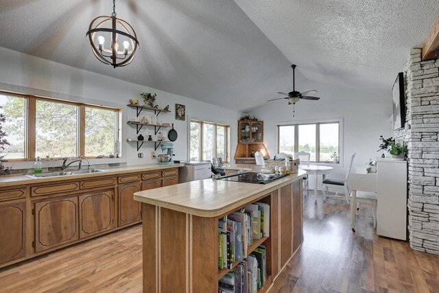 kitchen featuring decorative light fixtures, light hardwood / wood-style flooring, a wealth of natural light, and lofted ceiling