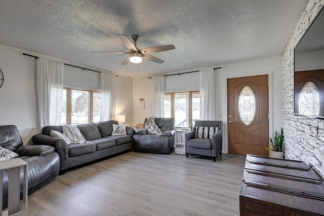 living room with ceiling fan, a textured ceiling, and light hardwood / wood-style flooring