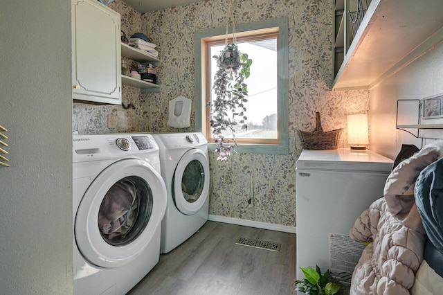 washroom featuring cabinets, independent washer and dryer, and light hardwood / wood-style flooring