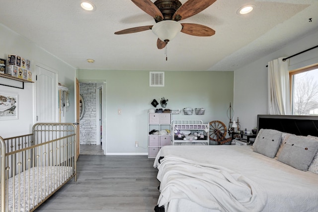 bedroom with hardwood / wood-style flooring, ceiling fan, and a textured ceiling