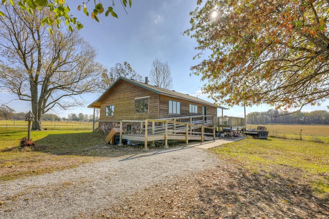 log-style house with a rural view, a deck, and a front lawn