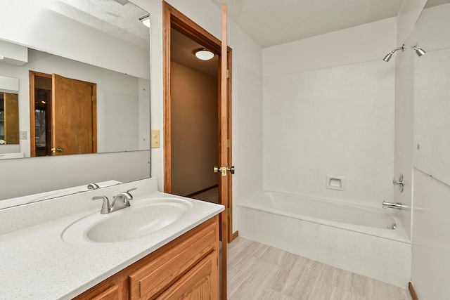 bathroom featuring a textured ceiling, vanity, shower / bath combination, and hardwood / wood-style flooring