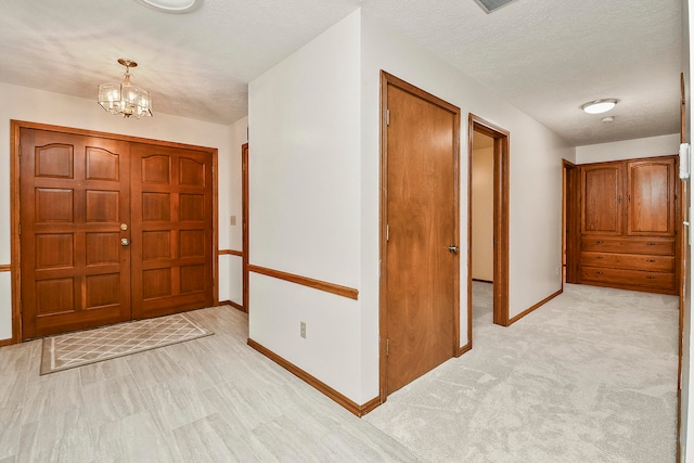 foyer featuring light carpet, a chandelier, and a textured ceiling