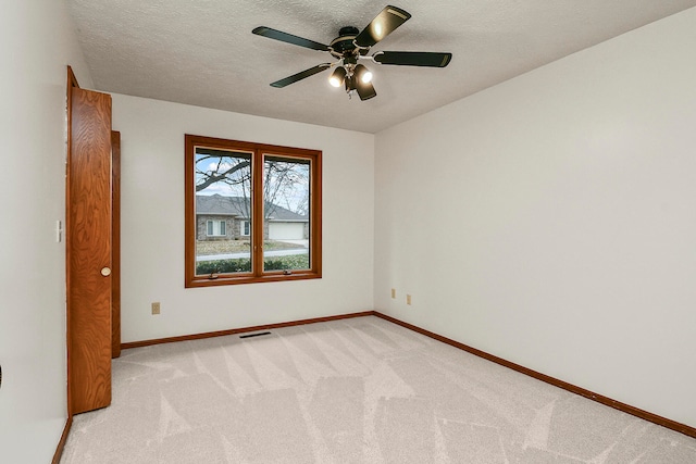 carpeted spare room with a textured ceiling and ceiling fan