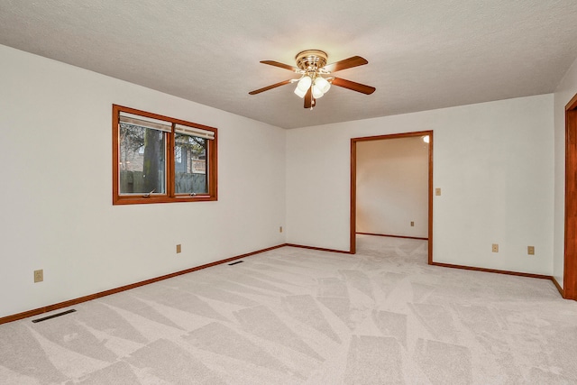 spare room with a textured ceiling, ceiling fan, and light carpet