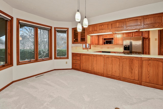 kitchen featuring pendant lighting, light carpet, and appliances with stainless steel finishes