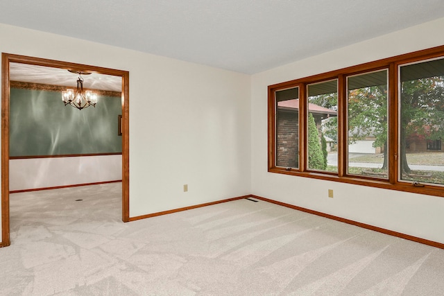 empty room featuring light carpet and a chandelier