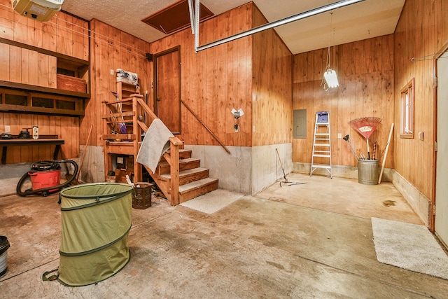 basement with electric panel and wooden walls