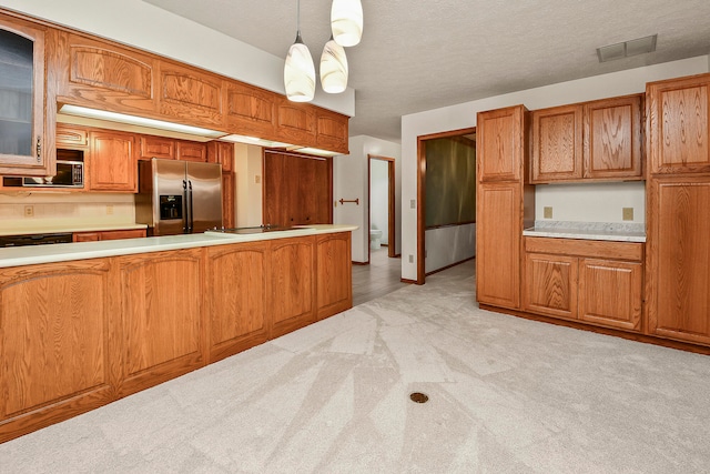 kitchen featuring a textured ceiling, light colored carpet, decorative light fixtures, and appliances with stainless steel finishes