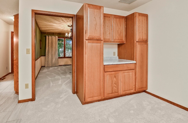 kitchen featuring a chandelier, light colored carpet, and a textured ceiling