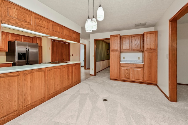 kitchen with a textured ceiling, light colored carpet, pendant lighting, and stainless steel refrigerator with ice dispenser