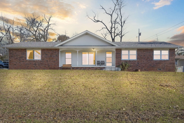 back house at dusk with a lawn and a porch