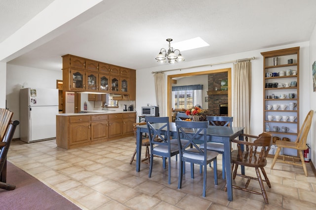 364 W Rd, Branson, MO 65616 - dining space featuring a chandelier, a brick fireplace, and a skylight