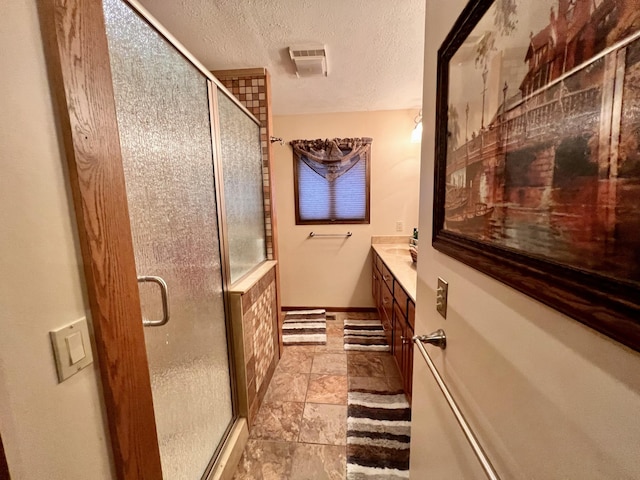 bathroom with vanity, a textured ceiling, and walk in shower