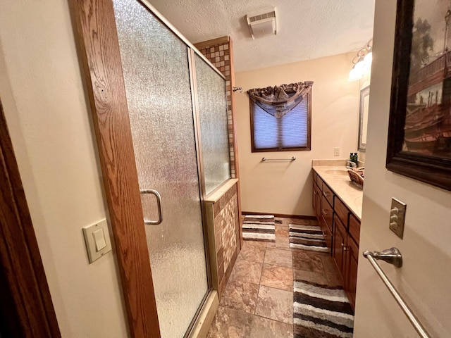 bathroom featuring a textured ceiling, vanity, and an enclosed shower