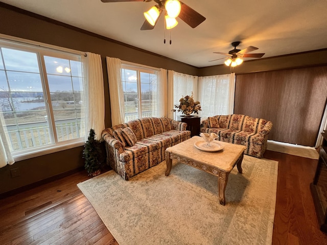 living room with ceiling fan, plenty of natural light, a water view, and wood-type flooring