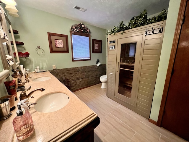 bathroom with a textured ceiling, vanity, and toilet