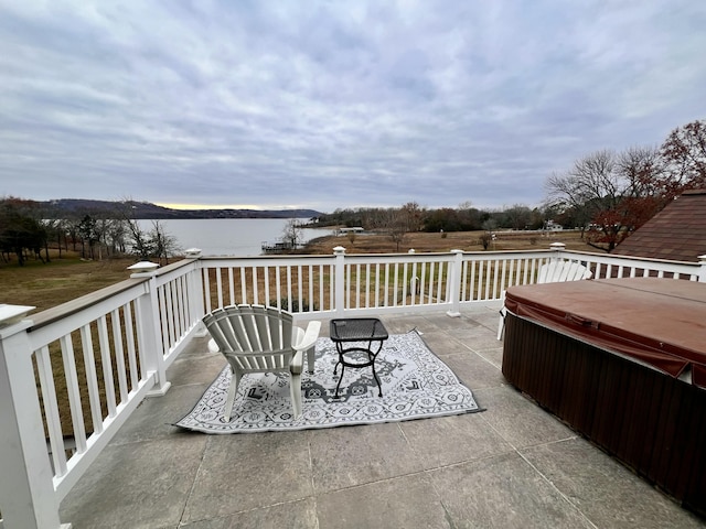 view of patio / terrace featuring a water view and a hot tub