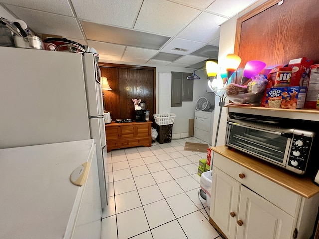 kitchen featuring a paneled ceiling, white cabinets, light tile patterned floors, and white refrigerator