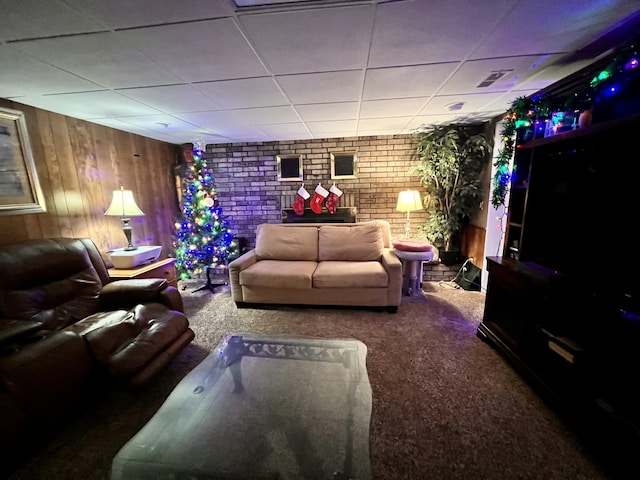 living room with carpet flooring, a drop ceiling, brick wall, and wooden walls