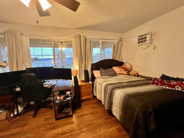 bedroom featuring hardwood / wood-style floors, ceiling fan, and an AC wall unit