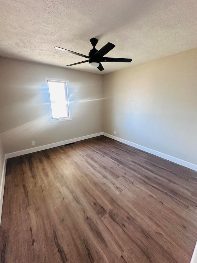 unfurnished room featuring a textured ceiling, ceiling fan, and dark wood-type flooring