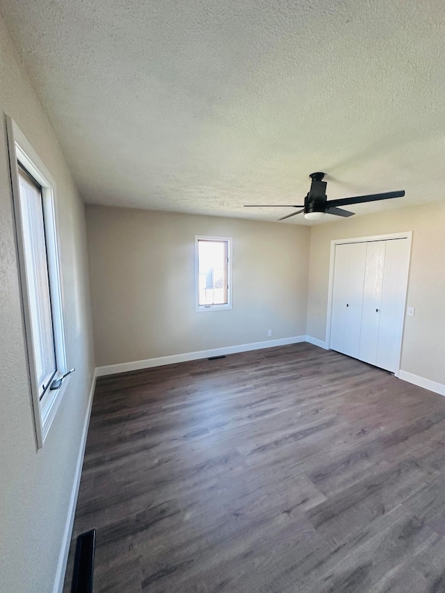 unfurnished bedroom featuring a textured ceiling, ceiling fan, dark wood-type flooring, and a closet