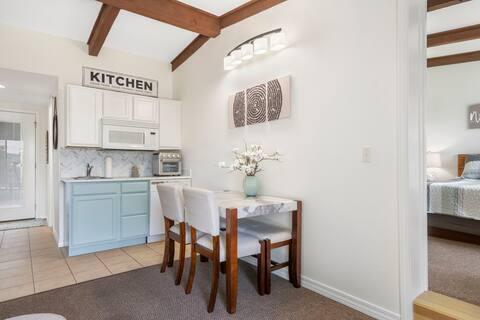 kitchen featuring backsplash, blue cabinetry, light tile patterned floors, white cabinets, and vaulted ceiling with beams