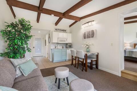 tiled living room featuring lofted ceiling with beams