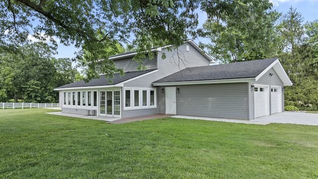 rear view of house featuring a lawn and a garage