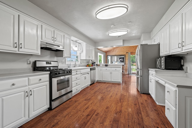 kitchen featuring kitchen peninsula, appliances with stainless steel finishes, dark wood-type flooring, sink, and white cabinetry