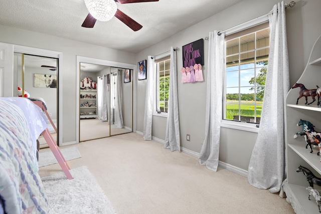 bedroom featuring ceiling fan, light colored carpet, and a textured ceiling