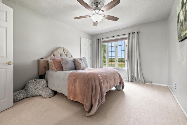 bedroom with ceiling fan, carpet floors, and a textured ceiling