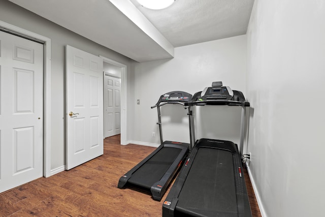 workout room featuring a textured ceiling and dark wood-type flooring