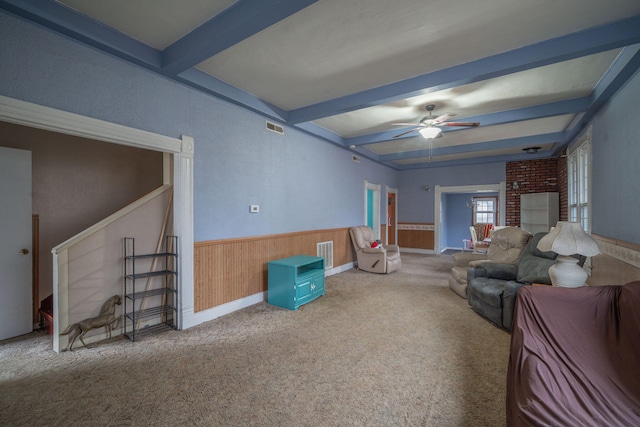 living room featuring carpet, ceiling fan, beam ceiling, and wooden walls