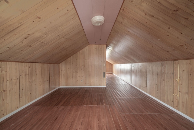 additional living space featuring hardwood / wood-style flooring, lofted ceiling, and wooden walls