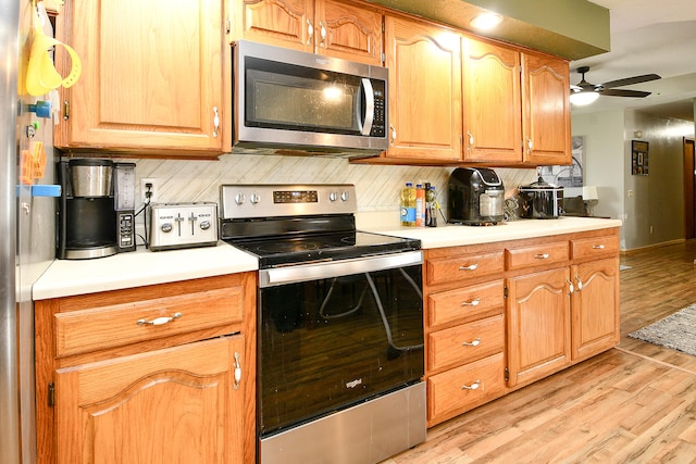 kitchen with decorative backsplash, appliances with stainless steel finishes, light hardwood / wood-style flooring, and ceiling fan