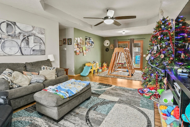 living room with hardwood / wood-style floors, a raised ceiling, and ceiling fan