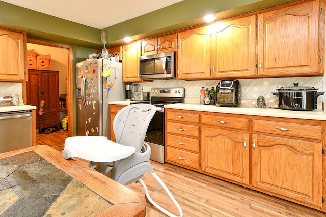 kitchen featuring light wood-type flooring, stainless steel appliances, and tasteful backsplash