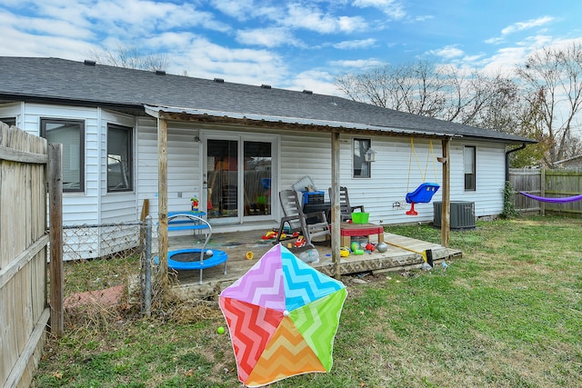 rear view of house with central AC unit and a yard