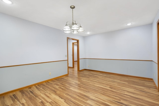 empty room with an inviting chandelier and light hardwood / wood-style flooring